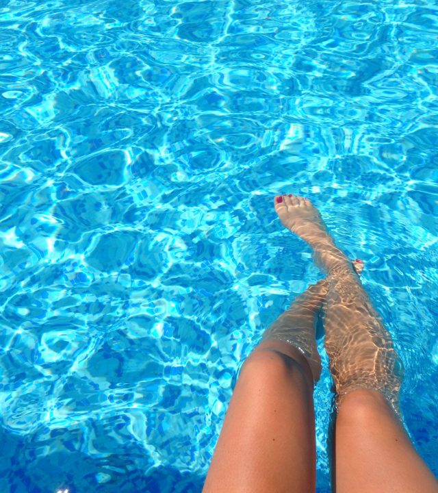Legs dipped in a shiny swimming pool with aquatic texture.